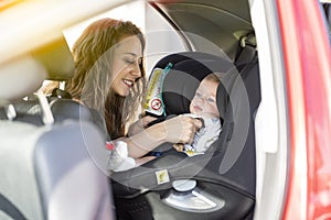 Mother fasten her son in the car seat and putting on his seat belt