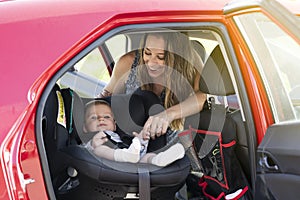 Mother fasten her son in the car seat and putting on his seat belt