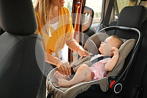 Mother fastening baby to child safety seat inside