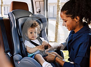 Mother fastening her little son safely in a car