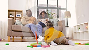 Mother, father and baby playing toy blocks at home