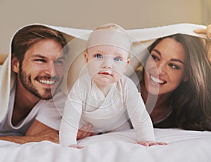 Mother, father and baby under blanket on bed for love, care and quality time together. Portrait of playful child, happy