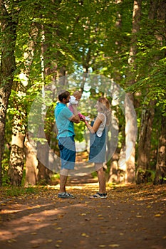 Mother, father and baby walking in the park.