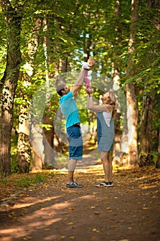 Mother, father and baby walking in the park.