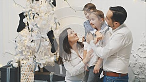 Mother, father and brother becalm little crying daughter on the white Christmas background.