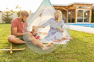 Mother and father camping with their baby boy in the backyard by the swimming pool