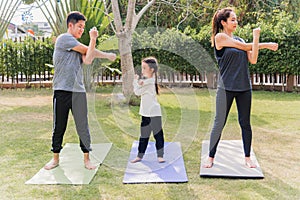 Mother, father and child daughter practicing exercising stretching together before yoga