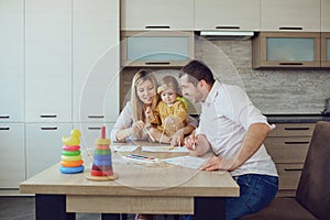 Mother, father and child draw together at the table.