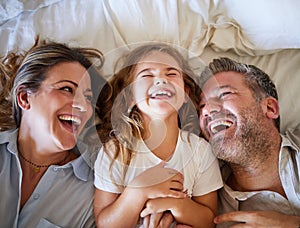 Mother, father and child happy in bed together in the morning, laughing at joke and bonding in house. Family with love