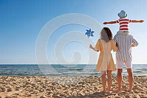 Mother, father and child having fun on the beach. Summer vacation and travel concept