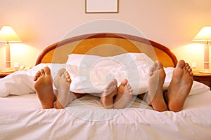 Mother, father and child lie on soft bed