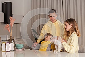 Mother and father with child son and white dog, three abstract plastic bottles on the white table