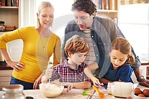 Mother, father and children in kitchen baking cookies for learning, development and bonding as family. Mom, dad and kids
