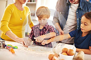 Mother, father and children in kitchen baking cookies for learning, development and bonding as family. Mom, dad and kids