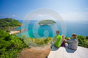 Mother, father and daughter embraces and sit on tropical island