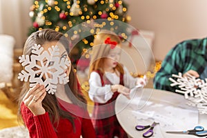 Mother, father and daughter making paper snowflakes