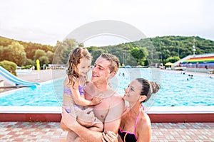 Mother, father and daughter near swimming pool. Sunny summer.