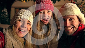 Mother, father, daughter taking selfie at snowing weather.