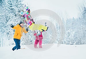 Mother and father family fooling in snow forest by throwing their little daugher to snowdrift photo