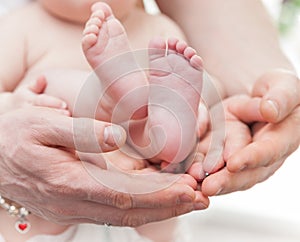 Mother and father gently hold baby legs in hands