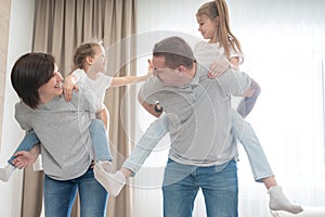 Mother And Father Giving daughters Piggyback in living room