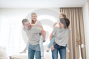 Mother And Father Giving daughters Piggyback in living room