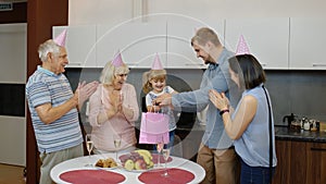 Mother, father and grandparents giving gift bag for child girl. Celebrating birthday anniversary