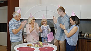 Mother, father and grandparents giving gift bag for child girl. Celebrating birthday anniversary