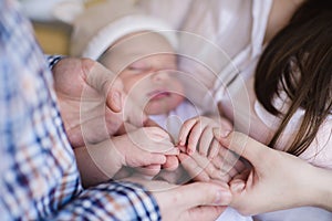 Mother and father holding hand of sleeping baby