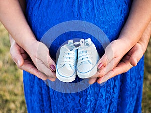 Mother and father holding in their hands a pair of tiny baby sneakers