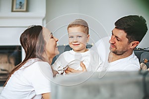 Mother and father hugging their little son on a couch