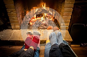 Mother father and kids sitting at cosy fireplace on Christmas time - Lovely family resting together on woolen socks at home fire photo