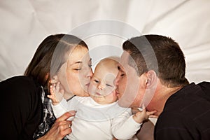 Mother and father kissing their baby girl