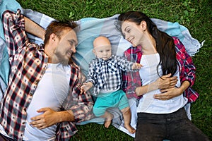 Mother, father and little baby leisures on grass