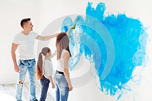 Mother, father and little daughter painting the wall in their new home.