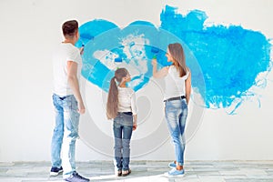 Mother, father and little daughter painting the wall in their new home.