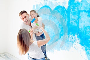 Mother, father and little daughter painting the wall in their new home.