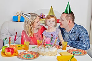 Mother, father and little daughter sit together on