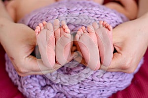 Mother and father`s hands cradling twin babies feet