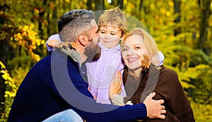 Mother, father and son on autumn walk in park. Happy family. Parents and child relaxing together in sunny day.