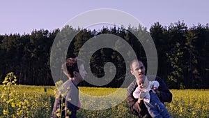 Mother, father and son dancing and playing in the rapeseed field