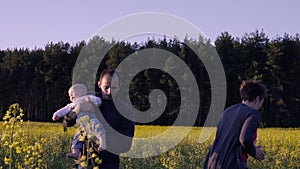 Mother, father and son dancing and playing in the rapeseed field