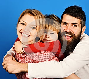 Mother, father and son with smiling faces hug on blue