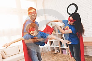 Mother, father and son in suits of superheroes. Incredibles in a bright room.