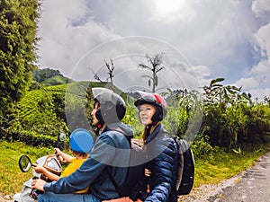 Mother, Father and son are traveling on a moped on a tea plantation in Malaysia. Traveling with children concept