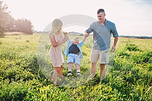 Mother and father swinging son in sunnny summer day