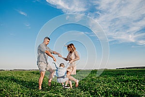 Mother and father swinging son in sunnny summer day