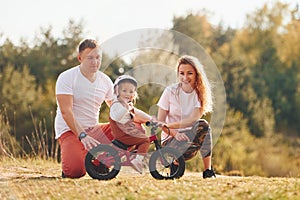 Mother and father teaching daughter how to ride bicycle outdoors