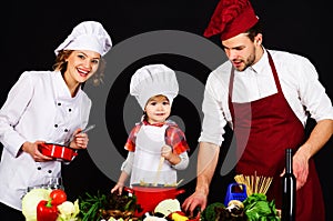 Mother and father teaching son to cook. Happy family in chef uniform preparing breakfast, dinner or supper. Healthy food