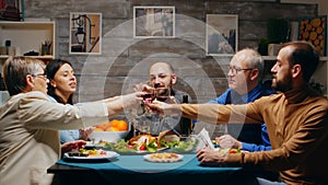 Mother and father in their sixties clinking glasses of red wine